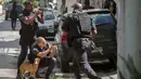 Para polisi militer Rio de Janeiro mengambil posisi saat melakukan operasi penggerebekan di daerah kumuh Cidade de Deus di Rio de Janeiro, Brasil (1/2). (AFP Photo/Mauro Pimentel)