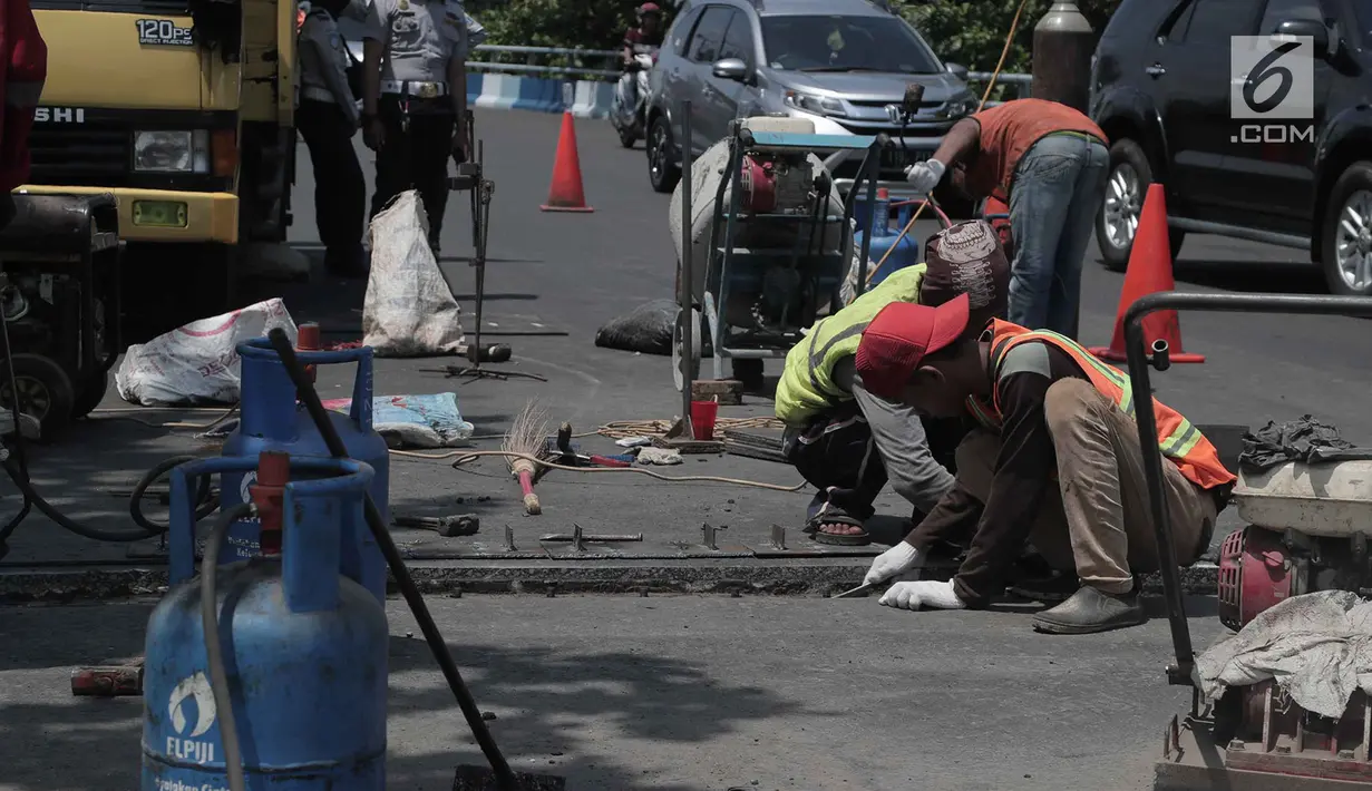 Para pekerja memperbaiki aspal di flyover Kemayoran yang mengalami kerenggangan, Jakarta, Sabtu (5/1). Hal itu disebabkan rusaknya sambungan celah sambungan alias expansion joint. (Merdeka.com/Imam Buhori)