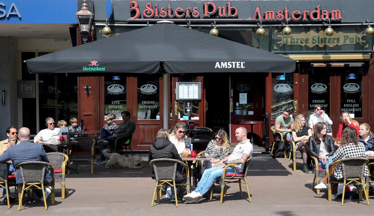 Pelanggan duduk di teras sebuah kafe di Amsterdam, Rabu (28/4/2021). Pemerintah Belanda mulai melonggarkan pembatasan ketat terkait Covid-19, mengakhiri jam malam yang kontroversial dan mengizinkan kafe untuk buka di luar ruangan. (REMKO DE WAAL/ANP/AFP)