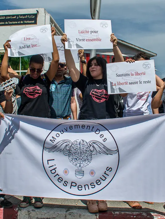 Para demonstran Tunisia membentangkan spanduk selama protes terhadap pemilik restoran dan bar yang menutup tokonya selama puasa bulan suci Ramadan di Tunis, Tunisia, (27/5). (AP Photo / Hassene Dridi)