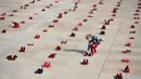 Seorang anak di antara instalasi ratusan sepatu merah untuk memprotes kekerasan terhadap perempuan di Habima Square, Tel Aviv, Selasa (4/12). Sepanjang tahun ini, 24 perempuan Israel tewas akibat tindakan kekerasan dalam rumah tangga. (AP/Oded Balilty)