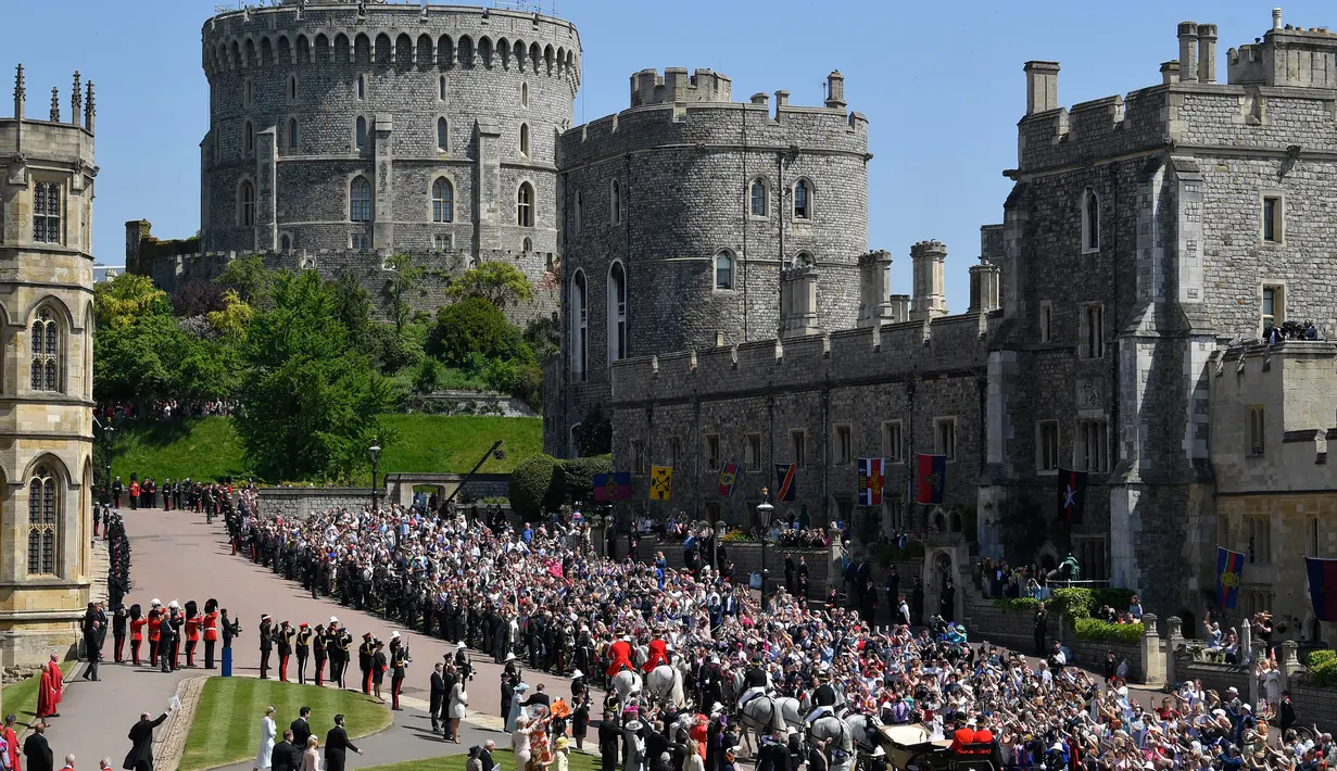 Pangeran Harry dan istri, Meghan Markle menaiki kereta kencana setelah upacara pernikahan mereka di Kastil Windsor, Inggris, Sabtu (19/5). Warga Inggris bersuka cita menyambut pernikahan Pangeran Harry dengan Meghan Markle. (TOBY MELVILLE/POOL/AFP)