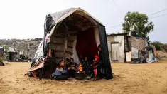 Warga Palestina menghangatkan diri di sekitar api tungku di area permukiman kumuh sebuah kamp pengungsi saat cuaca badai di Kota Khan Younis, Jalur Gaza selatan, pada 26 November 2020. (Xinhua/Yasser Qudih)