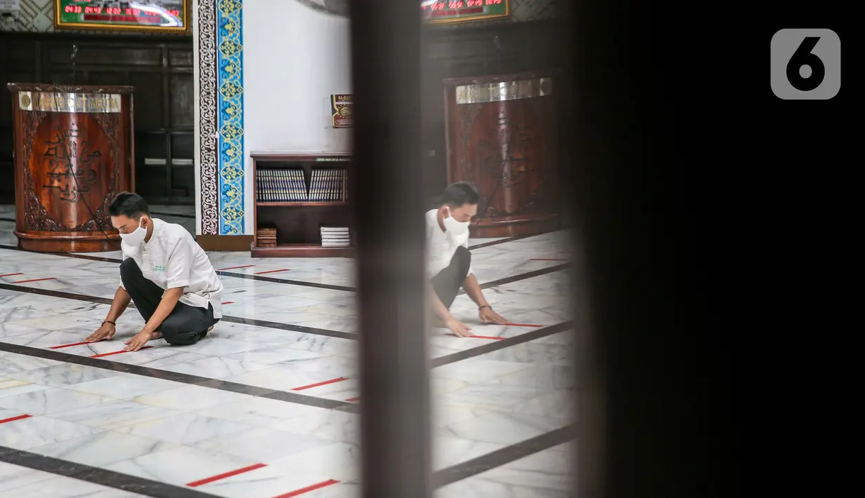 Petugas memasang tanda batas shaf di Masjid Cut Meutia, Jakarta, Kamis (30/7/2020). Masjid Cut Meutia akan menggelar Salat Idul Adha esok hari dengan menerapkan protokol kesehatan pencegahan Covid-19. (Liputan6.com/Faizal Fanani)