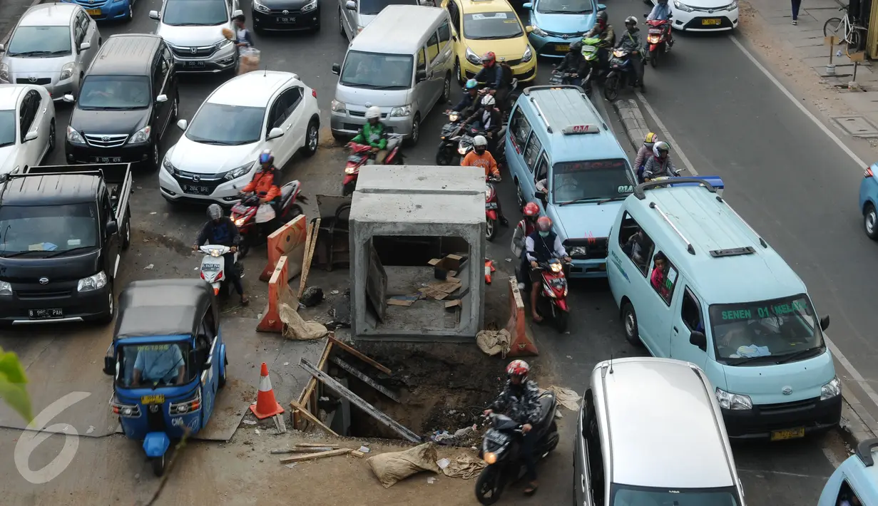 Pengendara motor menghindari lubang besar saluran air di perempatan Jalan Matraman Raya, Jakarta, Selasa (19/1/2016). Jalan Matraman Raya yang mengarah Kramat Raya macet parah imbas dari perbaikan saluran air. (Liputan6.com/Helmi Fithriansyah)