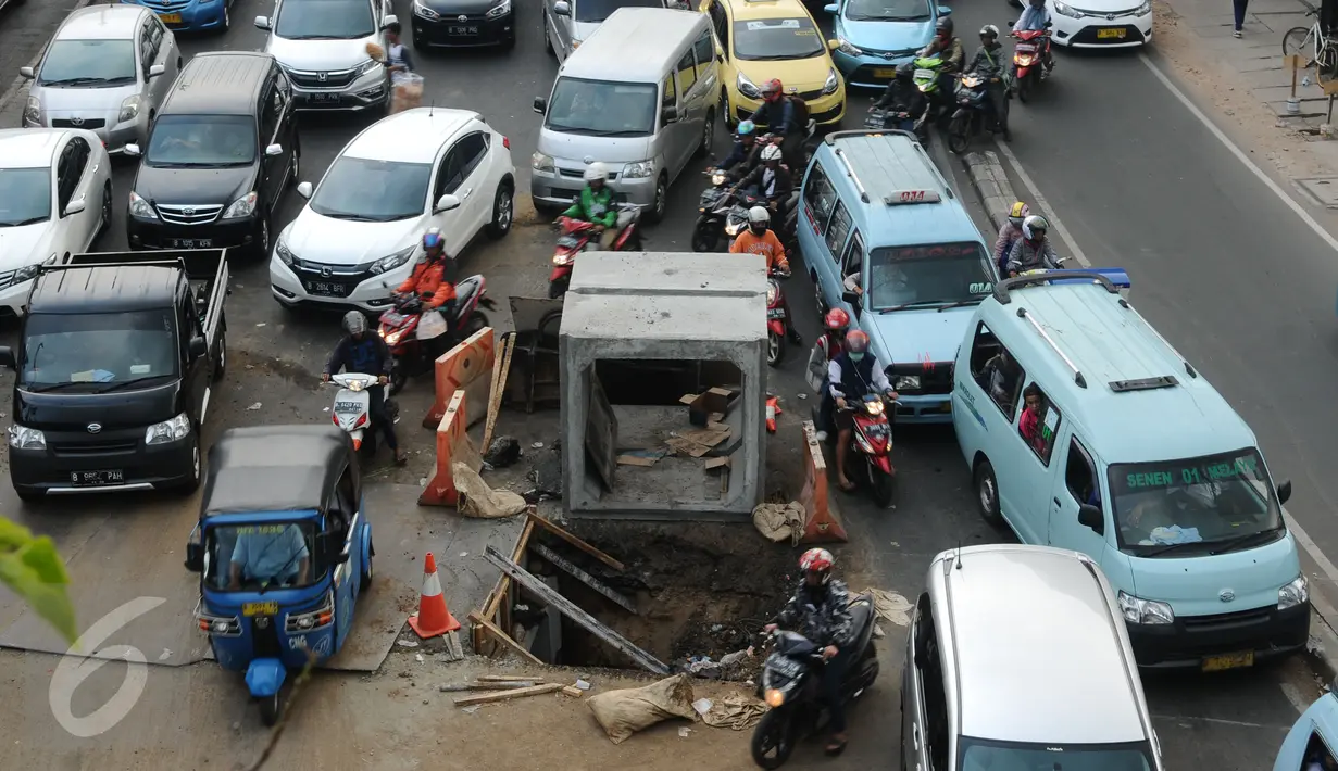 Pengendara motor menghindari lubang besar saluran air di perempatan Jalan Matraman Raya, Jakarta, Selasa (19/1/2016). Jalan Matraman Raya yang mengarah Kramat Raya macet parah imbas dari perbaikan saluran air. (Liputan6.com/Helmi Fithriansyah)