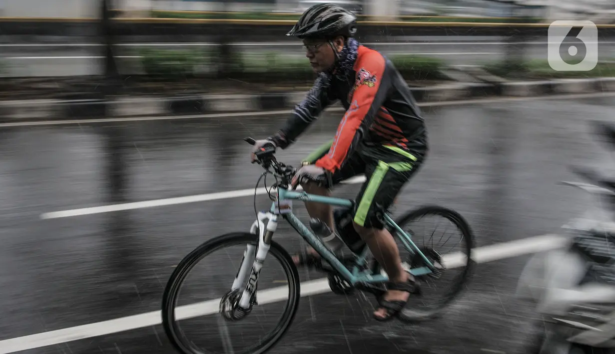 Pesepeda saat menerobos hujan di Jalan Pramuka, Jakarta, Kamis (18/2/2021). Badan Meteorologi Klimatologi dan Geofisika (BMKG) mengimbau pengguna jalan agar berhati-hati saat berkendara karena hujan disertai angin kencang diprediksi terus berlanjut hingga akhir Februari (merdeka.com/Iqbal S Nugroho)