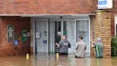 Staf Klub Olahraga Camden mengarungi banjir untuk masuk ke gedung di pinggiran barat daya Camden, Sydney, Australia, Selasa (8/3/2022). (Muhammad FAROOQ/AFP)