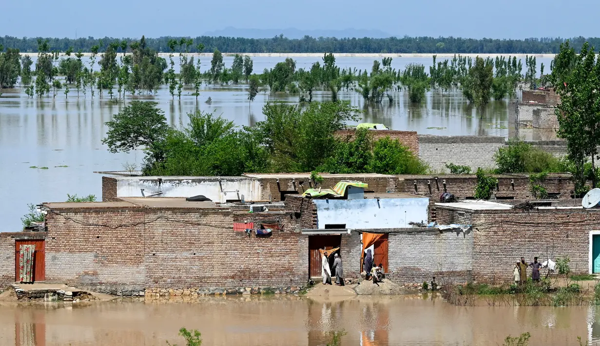 Orang-orang berdiri di rumah mereka yang terendam banjir setelah hujan lebat di distrik Nowshera, Provinsi Khyber-Pakhtunkhwa, Pakistan pada tanggal 16 April 2024. (Abdul MAJEED/AFP)