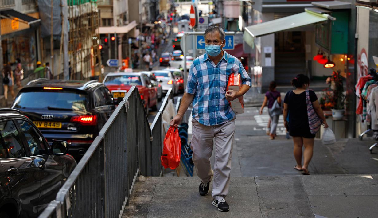 Seorang pria yang mengenakan masker berjalan di sepanjang jalan di Hong Kong, Rabu (22/7/2020). Hong Kong menghadapi "tahap kritis" dalam perjuangannya melawan COVID-19, dan pemerintah sedang memperpanjang langkah-langkah baru untuk menjaga jarak sosial. (AP Photo/Kin Cheung)