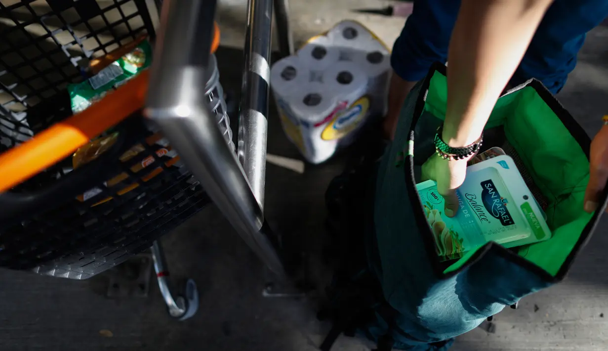 Pelanggan memasukkan belanjaannya dari troli ke dalam tas punggung saat meninggalkan toko kelontong di Mexico City, 1 Januari 2020. Berdasarkan undang-undang baru yang berlaku, pasar swalayan akan didenda jika memberi kantong plastik kepada pelanggan mereka. (AP/Rebecca Blackwell)