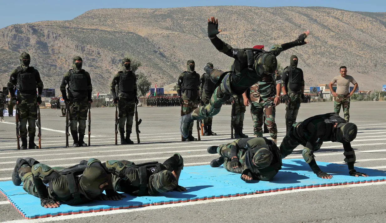 Perwira Peshmerga menunjukkan keterampilan mereka saat mengambil bagian dalam upacara kelulusan di Kota Soran, Irak, Rabu (16/10/2019). Latihan pasukan bersenjata Kurdi tersebut dilakukan sekitar 100 kilometer timur laut ibu kota otonomi wilayah Kurdi di Irak, Arbil. (SAFIN HAMED/AFP)