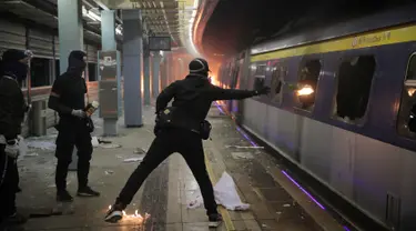 Seorang pelajar melempar bom molotov ke dalam kereta yang terparkir di Stasiun MTR Chinese University, Hong Kong, Rabu (13/11/2019). Gerakan antipemerintah Hong Kong yang telah berlangsung selama lima bulan bertindak semakin keras. (AP Photo/Kin Cheung)