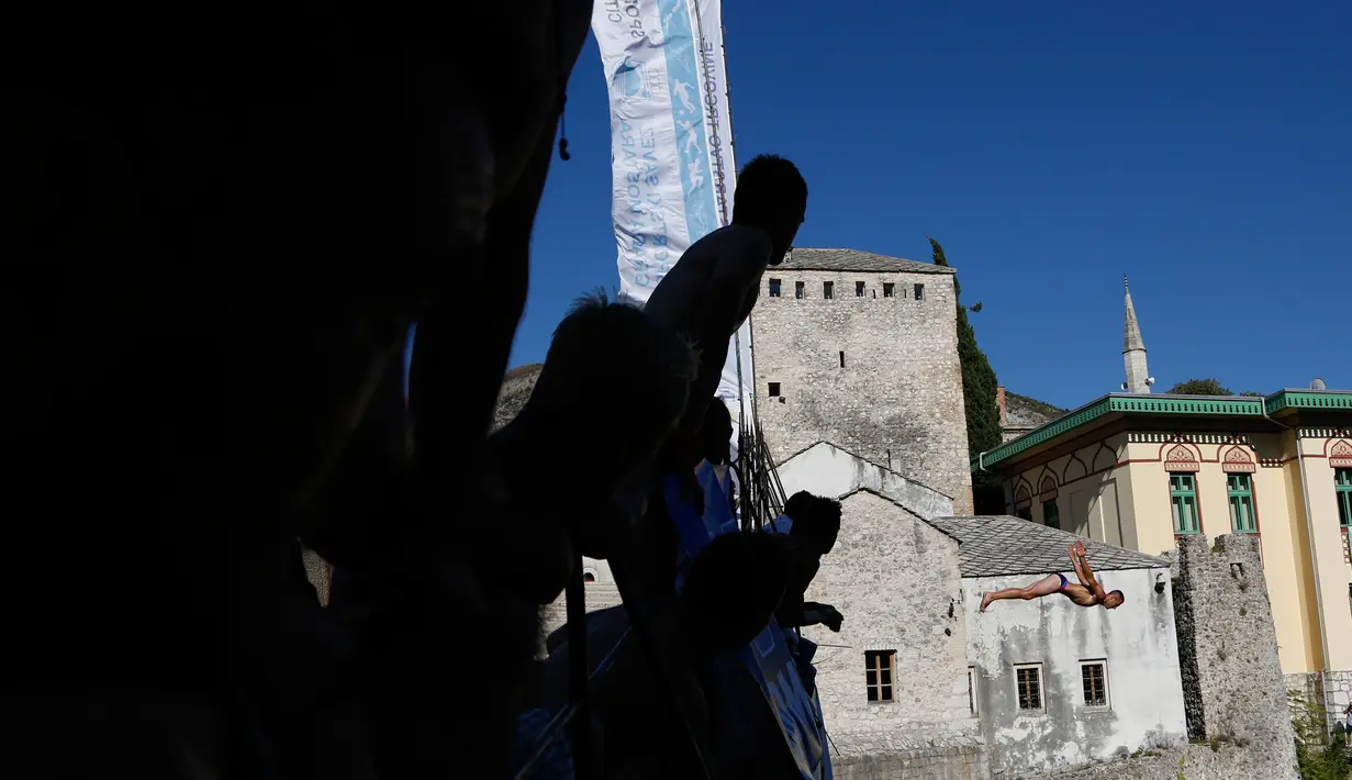 Penonton menyaksikan peserta melompat dari jembatan Mostar selama kompetisi menyelam tradisional ke 451 di Mostar, Bosnia, Minggu (30/7). Total 41 peserta dari Bosnia dan negara tetangga mengikuti kompetisi menyelam tahunan tersebut. (AP Photo/Amel Emric)