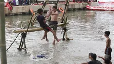 Dua peserta berusaha saling menjatuhkan saat mengikuti lomba gebuk bantal dalam Festival Kalimalang di Cipinang Melayu, Jakarta Timur, Kamis (17/8). Festival Kalimalang ini dalam rangka memeriahkan HUT ke-72 RI. (Liputan6.com/Herman Zakharia)