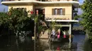Anak-anak menaiki sampan di luar rumah yang banjir usai hujan lebat di Desa Obot, sekitar 100 kilometer (60 mil) barat laut Tirana, Albania, Senin (11/1/2021). Pihak berwenang mengevakuasi banyak warga menyusul banjir yang merendam ribuan hektare (acre) kawasan di Albania. (AP Photo/Hektor Pustina)