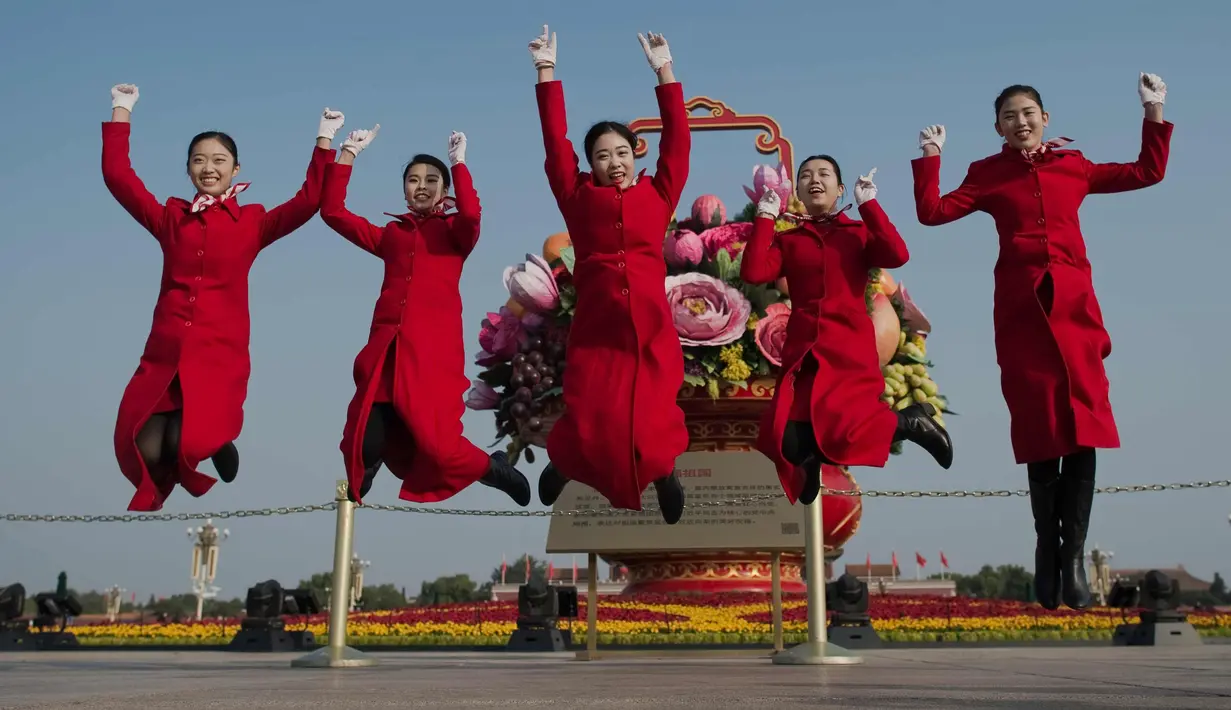 Para pemandu melompat di lapangan Tiananmen selama sesi penutupan Kongres Partai Komunis ke-19 di Beijing (24/10). Kongres Partai Komunis ke-19 secara resmi mengangkat Xi Jinping sebagai penguasa negara tersebut. (AFP Photo/ Nicolas Asfouri)