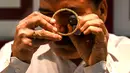 Gambar diambil pada 11 Agustus 2021 menunjukkan seorang manajer toko perhiasan memeriksa gelang emas di Mumbai, India. Putus asa mendapatkan uang tunai, banyak keluarga dan usaha kecil menjual perhiasan emas sebagai jaminan untuk mendapatkan pinjaman jangka pendek. (Punit PARANJPE/AFP)
