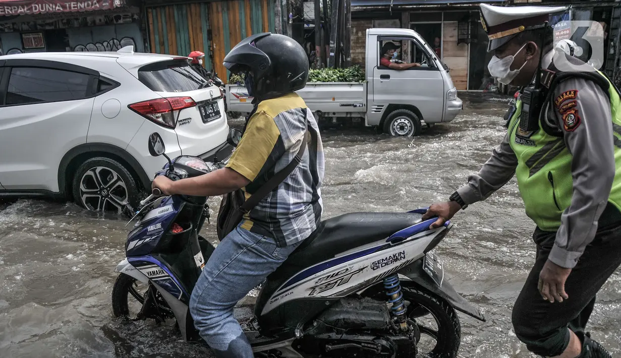 Petugas kepolisian mendorong sepeda motor warga yang mogok akibat menerobos banjir rob di Jalan Lodan Raya, Ancol, Jakarta, Senin (6/12/2021). BMKG mengimbau warga agar tetap waspada dengan kemungkinan terjadinya banjir rob selama sepekan ke depan. (merdeka.com/Iqbal S Nugroho)