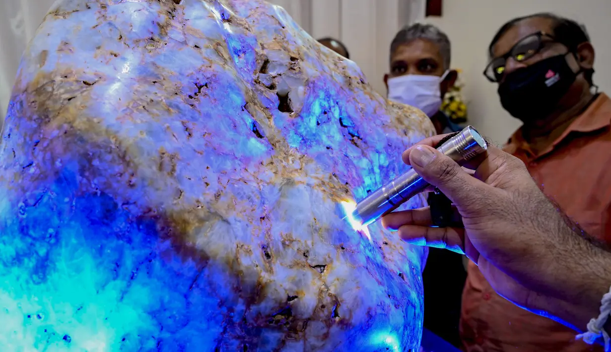 Orang-orang mengamati permata yang diklaim sebagai safir biru korundum alami terbesar di dunia di Horana, sekitar 45 km dari Kolombo, 12 Desember 2021. Ahli permata Sri Lanka mengatakan itu adalah salah satu permata paling langka di dunia karena beratnya lebih dari 300 kg. (Ishara S. KODIKARA/AFP)