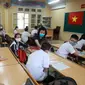 Seorang guru memeriksa suhu murid-muridnya sebelum memulai kelas di sekolah menengah Dinh Cong di Hanoi pada hari Senin. Siswa di seluruh Vietnam kembali bersekolah setelah tiga bulan belajar online. (Hau Dinh / AP)