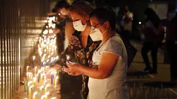 Orang-orang menyalakan lilin untuk mengenang mereka yang meninggal akibat virus corona di depan Kementerian Kesehatan di Asuncion, Paraguay, Minggu (14/3/2021). Sejauh ini, Paraguay mencatat 3.450 kasus kematian akibat COVID-19. (AP Photo/Jorge Saenz)