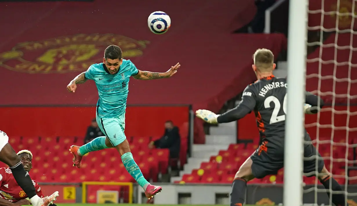Gelandang Liverpool, Roberto Firmino (tengah) melepaskan sundulan yang berbuah gol kedua timnya ke gawang Manchester United dalam laga lanjutan Liga Inggris 2020/2021 pekan ke-35 di Old Trafford, Kamis (13/5/2021). Liverpool menang 4-2 atas Manchester United. (AFP/Dave Thompson/Pool)