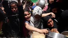 Warga Palestina berjuang untuk mendapatkan jatah makanan mereka di luar pusat distribusi di Beit Lahia, Jalur Gaza Utara pada 15 Mei 2025. (BASHAR TALEB/AFP)