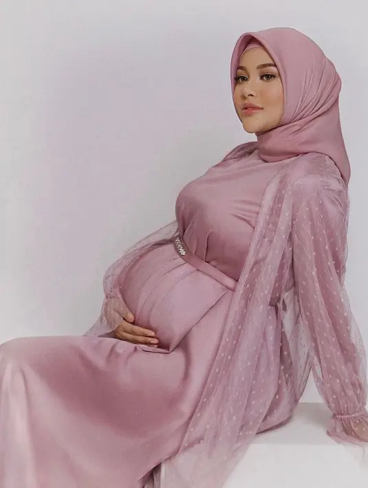 Jika ingin tampil anggun dan feminim ketika lebaran, kamu dapat memilih dress berwarna merah muda dengan outer transparan sebagai pemanis. (instagram/aurelie.hermansyah)