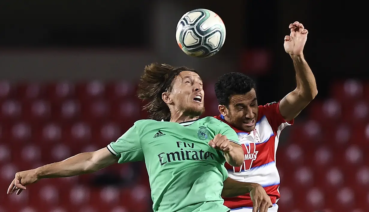 Gelandang Real Madrid, Luka Modric, berebut bola dengan bek Granada, Ismail Koybasi, pada laga lanjutan La Liga pekan ke-36 di di Estadio Nuevo Los Carmenes, Selasa (14/7/2020) dini hari WIB. Real Madrid menang 2-1 atas Granada. (AFP/Jorge Guerrero)