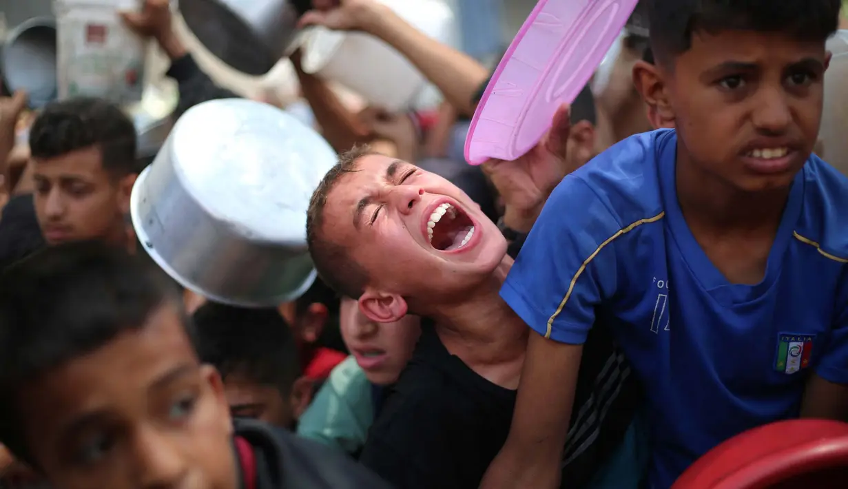 Anak-anak Palestina berkumpul untuk menerima makanan yang dimasak di sebuah titik distribusi di Nuseirat, Jalur Gaza Tengah, pada 11 Juni 2025. (Eyad BABA/AFP)
