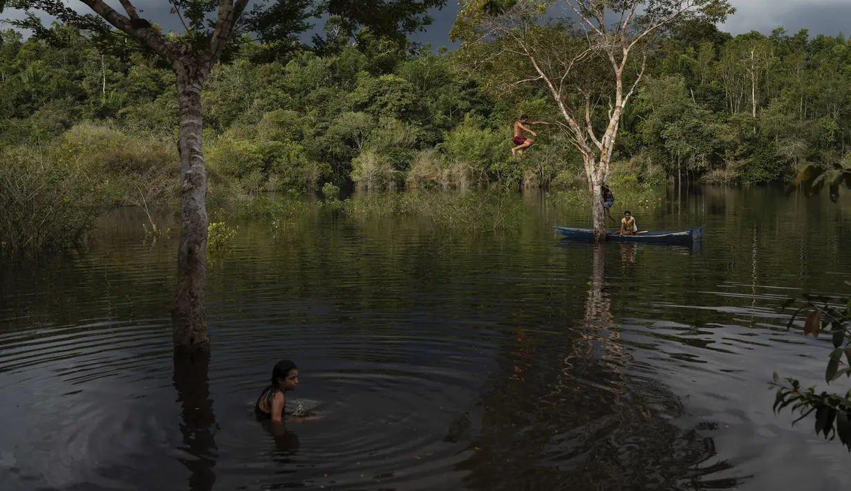 Anak-anak pribumi Sateré Mawé bermain di Sungai Tarumã Açu River, daerah Gaviao, dekat Manaus, Brasil, Jumat (29/5/2020). Penduduk asli Manaus di Brasil hidup bersama dalam lingkungan miskin tempat mereka berjuang untuk mempertahankan bahasa, budaya, dan identitas asli mereka. (AP Photo/Felipe Dana)