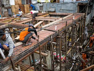 Para pekerja menyelesaikan pembangunan rumah panggung di dekat bantaran Kali Ciliwung, Kampung Melayu, Jakarta, Rabu (7/4/2021). Pemerintah Provinsi DKI Jakarta melakukan renovasi terhadap 40 hunian warga Kampung Melayu menjadi rumah panggung. (Liputan6.com/Faizal Fanani)