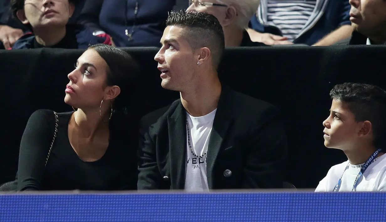 Pemain Juventus, Cristiano Ronaldo bersama sang kekasih, Georgina Rodriguez dan anaknya, Cristiano Jr menyaksikan Novak Djokovic menghadapi John Isner pada laga tenis dunia, ATP Finals 2018, di O2 Arena, London, Senin (12/11). (AP /Tim Ireland)