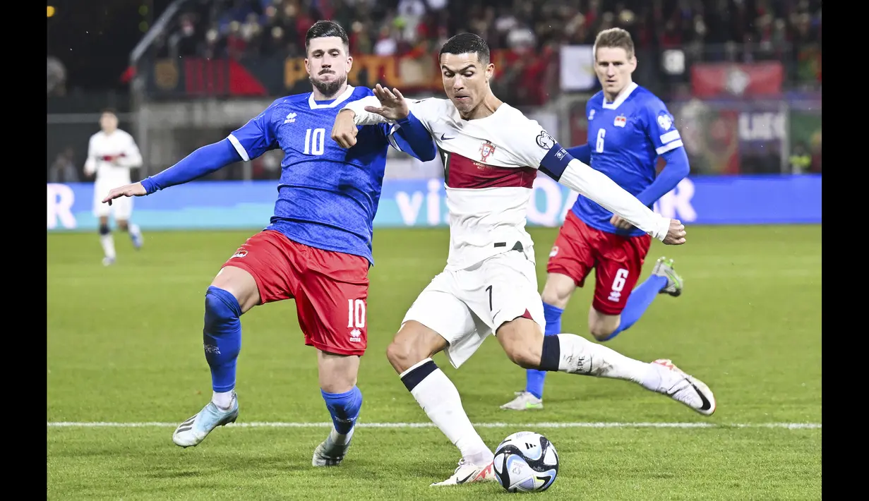 Striker Timnas Portugal, Cristiano Ronaldo (kanan) melepaskan tendangan yang menghasilkan gol pembuka ke gawang Liechtenstein pada laga lanjutan Grup J Kualifikasi Euro 2024 di Rheinpark Stadium, Vaduz, Jumat (17/11/2023) dini hari WIB. (AFP/Sebastien Bozon)