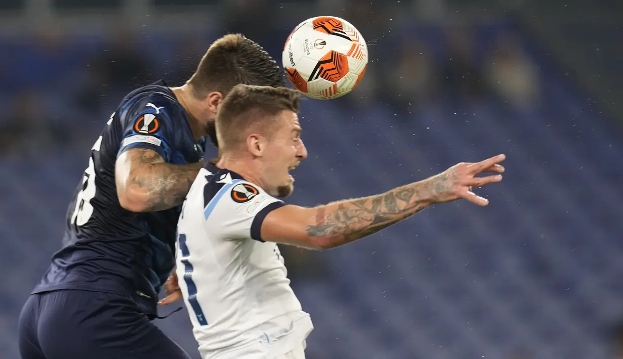Bek Olympique Marseille, Duje Caleta-Car dan gelandang Lazio Sergej Milinkovic-Savic melompat saat berebut bola pada matchday kedua Grup E Liga Europa 2021 di Stadion Olimpico Roma, Kamis (21/10/2021) malam WIB. Lazio hanya mampu bermain imbang 0-0 kala menjamu Marseille. (AP Photo/Gregorio Borgia)