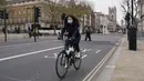 Seorang wanita mengenakan masker saat dia bersepeda di Westminster, di London, Kamis (16/12/2021). Inggris mencatat jumlah tertinggi infeksi COVID-19 baru yang dikonfirmasi pada hari Rabu (15/12) sejak pandemi dimulai. (AP Photo/Alberto Pezzali)