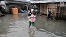 Seorang anak melintasi banjir rob yang menggenangi permukiman Muara Angke, Jakarta, Selasa (22/1). Banjir air laut pasang atau Rob yang kembali melanda kawasan itu sejak 6 hari lalu membuat aktivitas warga sekitar terganggu. (Merdeka.com/Iqbal S. Nugroho)