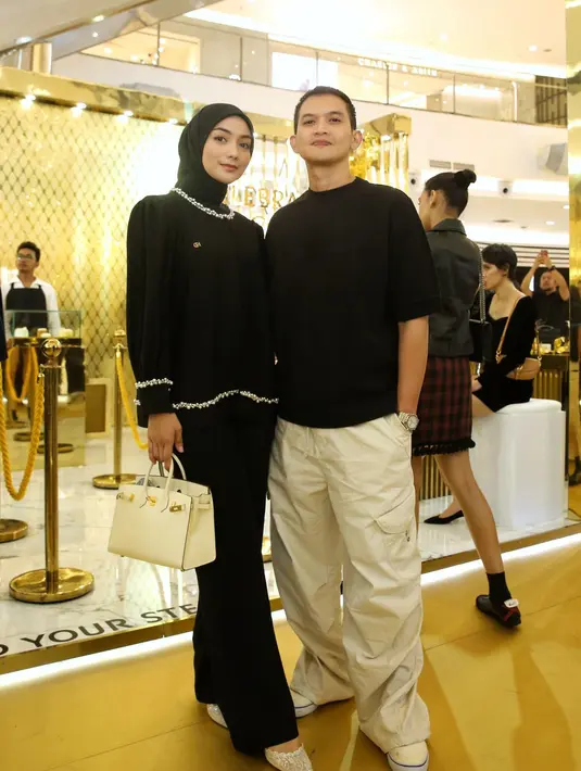 Citra Kirana dan Rezky Aditya tampil kasual dengan top hitam. Keduanya terlihat serasi dengan padanan celana dan tas off-white.  / Foto: Adrian - Fimela.com.