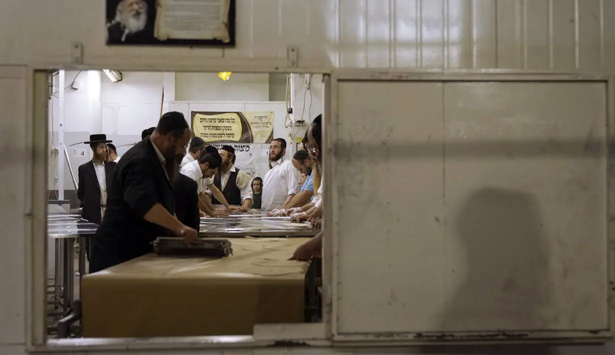Yahudi Ultra-Ortodoks menyiapkan matzoh khusus di sebuah toko roti di Ashdod, Israel, 11 April 2022. Matzoh adalah roti tradisional tidak beragi yang dibuat untuk Paskah. (AP Photo/Tsafrir Abayov)