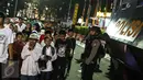 Warga yang sedang takbiran melintas didepan petugas Brimob yang berjaga-jaga dikawasan Bunderan HI, Jakarta, Selasa (6/7). (Liputan6.com/Faizal Fanani)