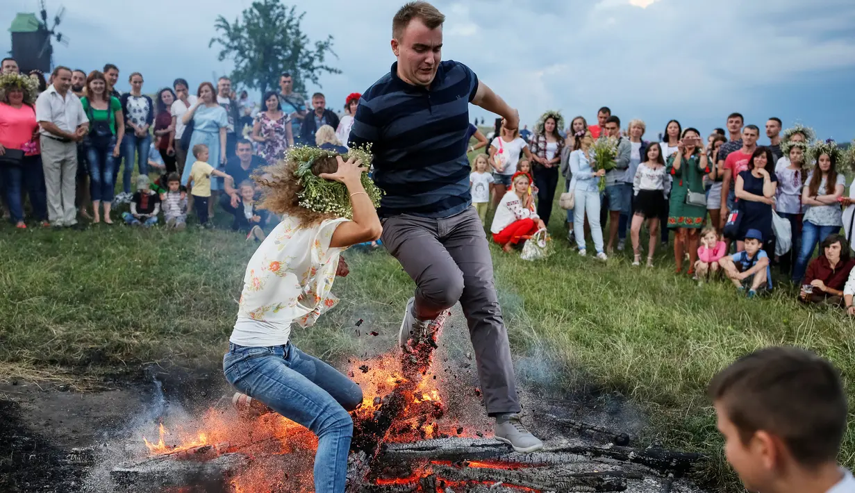 Warga melompati api unggun saat perayaan tradisional Ivan Kupala di Kiev, Ukraina, Rabu (6/7). Ivan's day merupakan tradisi pagan kuno sebagai ritual kesuburan di musim panas yang masih ada di Rusia dan Ukraina. (REUTERS/ Gleb Garanich)