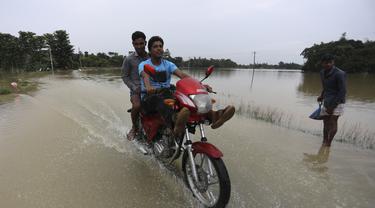 Seorang pengendara motor melewati jalan yang banjir di daerah Bagha di Sylhet, Bangladesh (23/5/2022). Banjir bandang pra-musim telah membanjiri bagian dari India dan Bangladesh, menewaskan sedikitnya 24 orang dalam beberapa pekan terakhir dan mengirim 90.000 orang ke tempat penampungan. (AP Photo)