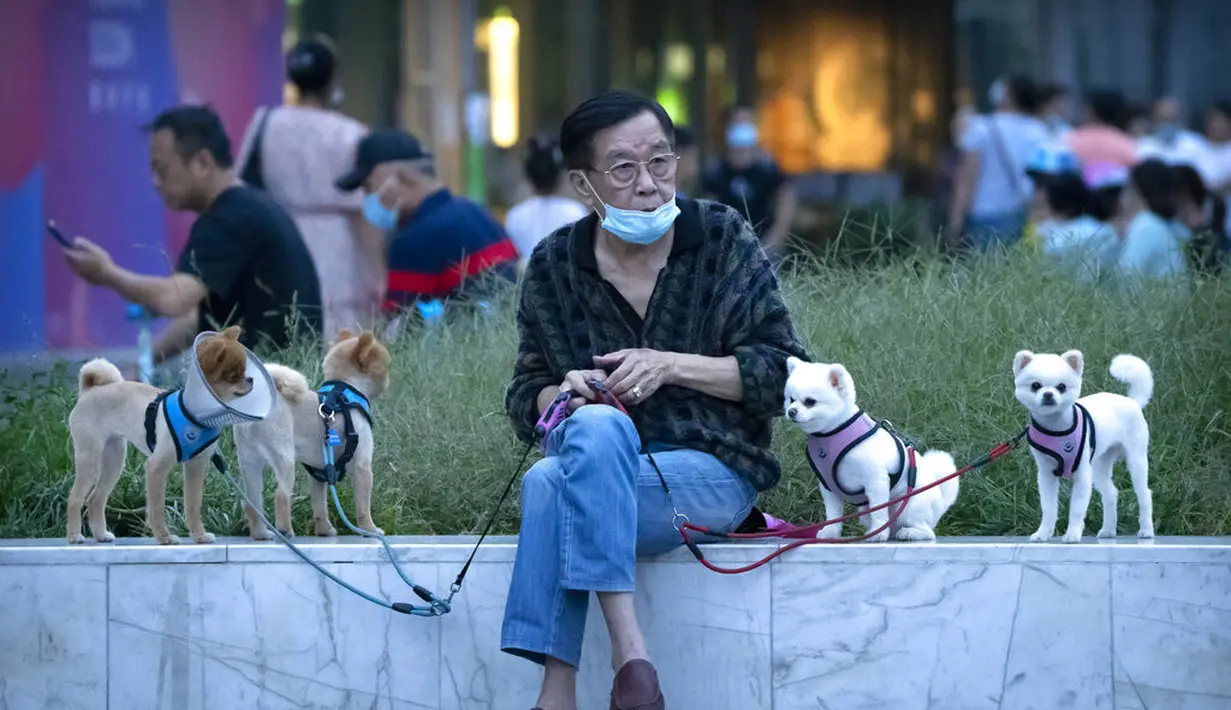 Seorang pria duduk dengan anjing di lingkungan dengan kasus dugaan virus corona di Beijing (15/9/2021). China memperketat penguncian dan meningkatkan pesanan untuk pengujian massal di kota-kota di sepanjang pantai timurnya di tengah lonjakan terbaru dalam kasus COVID-19. (AP Photo/Mark Schiefelbein)