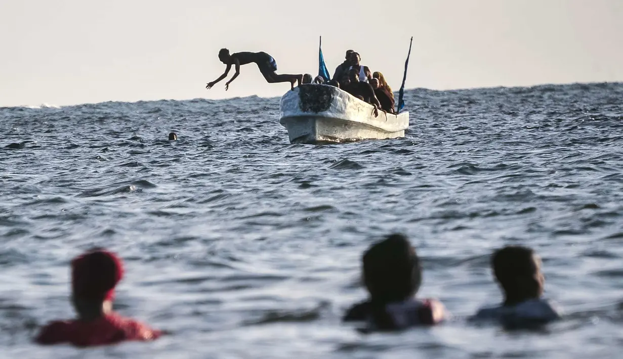 Seorang anak melompat dari sebuah kapal di Pantai Jazera di pinggiran Mogadishu, Somalia (24/11). Pantai ini jadi tempat rekreasi populer bagi warga Somalia. (AFP Photo/Mohamed Abdiwahab)