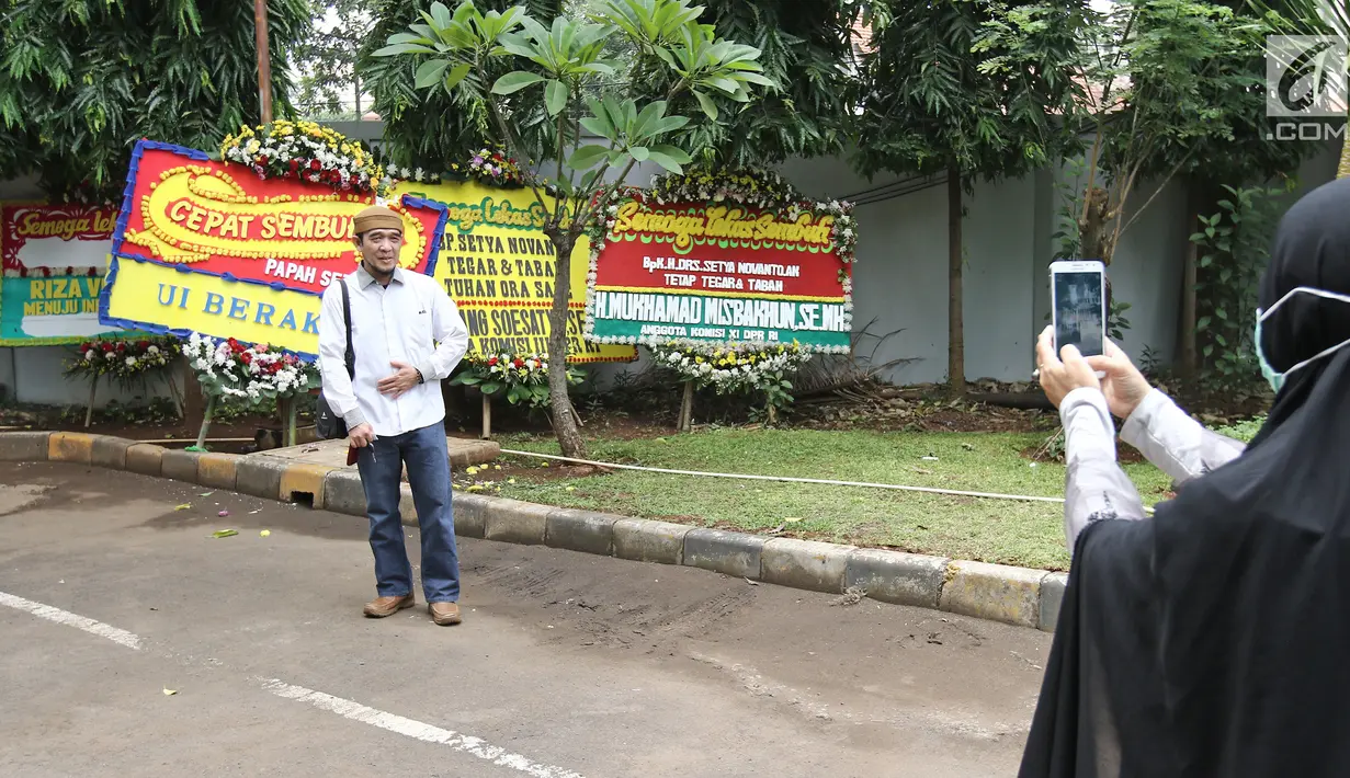 Seorang pria berfoto di depan karangan bunga untuk Ketua DPR, Setya Novanto di RSCM Kencana, Jakarta, Minggu (19/11). Sebelumnya, Novanto dirawat di Rumah Sakit Medika Permata Hijau setelah mengalami kecelakaan lalu lintas. (Liputan6.com/Herman Zakharia)