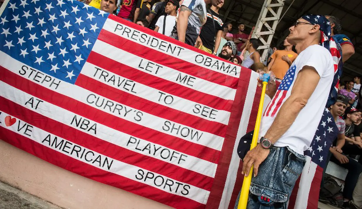 Suporter timnas Kuba berdiri di depan bendera Amerika Serikat. (AFP/Adalberto Roque)