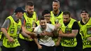 Segerombolan petugas keamanan, yang duduk di pinggir lapangan, kemudian berlari masuk lapangan untuk mengawal supporter itu pergi. (Fabrice COFFRINI / AFP)