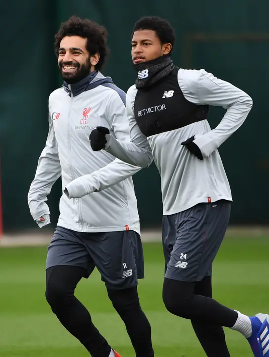 Gelandang Liverpool Mohamed Salah (kiri) berbincang dengan rekan setimnya Rhian Brewster saat sesi latihan jelang menghadapi Bayern Munchen dalam leg kedua babak 16 besar Liga Champions di Melwood, Liverpool, Inggris, Selasa (12/3). (Paul ELLIS/AFP)