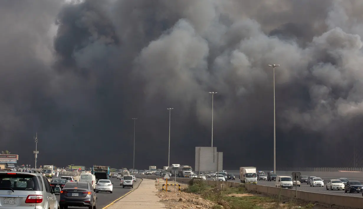 Mobil-mobil melaju saat asap hitam  membumbung menyelimuti gedung Stasiun Kereta Api Cepat Haramain di kota Jeddah, Arab Saudi, Minggu (29/9/2019). Akibat kebakaran tersebut, setidaknya sepuluh orang terluka. (Photo by - / AFP)